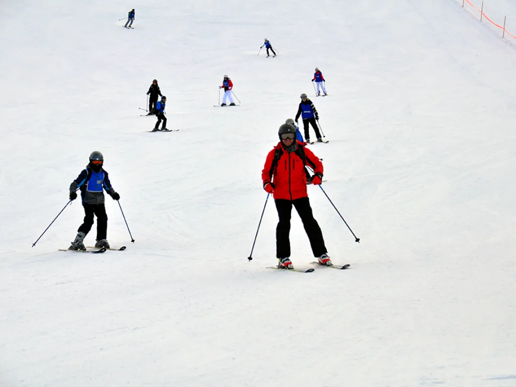 Zwei Skifahrende auf der Piste unterhalb der Station.